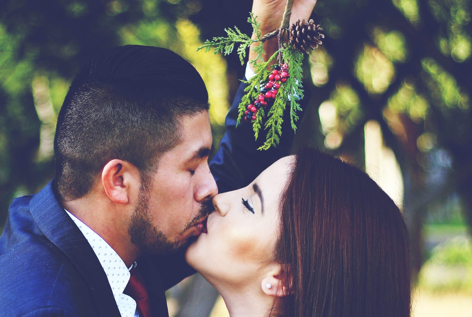 two people kissing beneath mistletoe